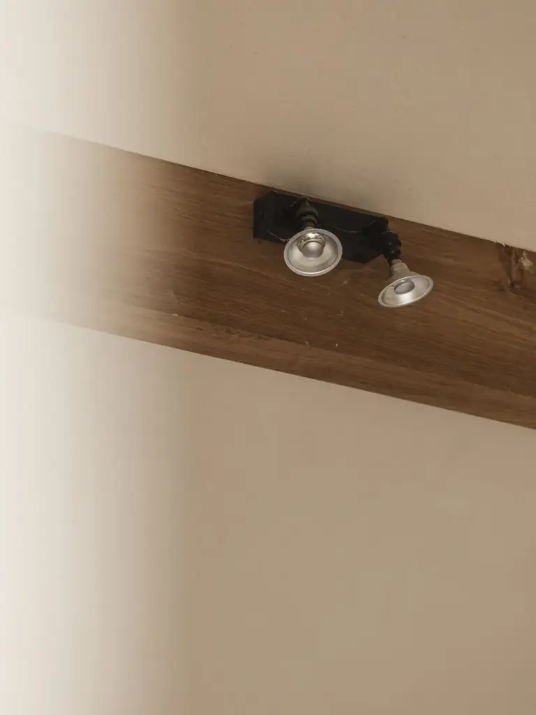 Twee richtbare spots op een eikenhouten balk, Landelijke woning in Torhout, interieur Laura Calleeuw