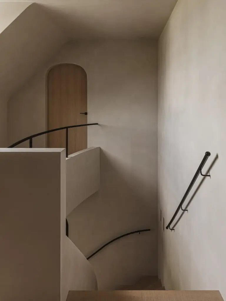 Trappenhuis met houten boogdeur, gebogen gepleisterde leuning en zwarte handgreep, Landelijke woning in Torhout, interieur Laura Calleeuw
