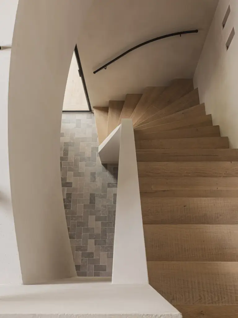 Gebogen trap in eikenhout met zicht op de klinkervloer beneden, Landelijke woning in Torhout, interieur Laura Calleeuw