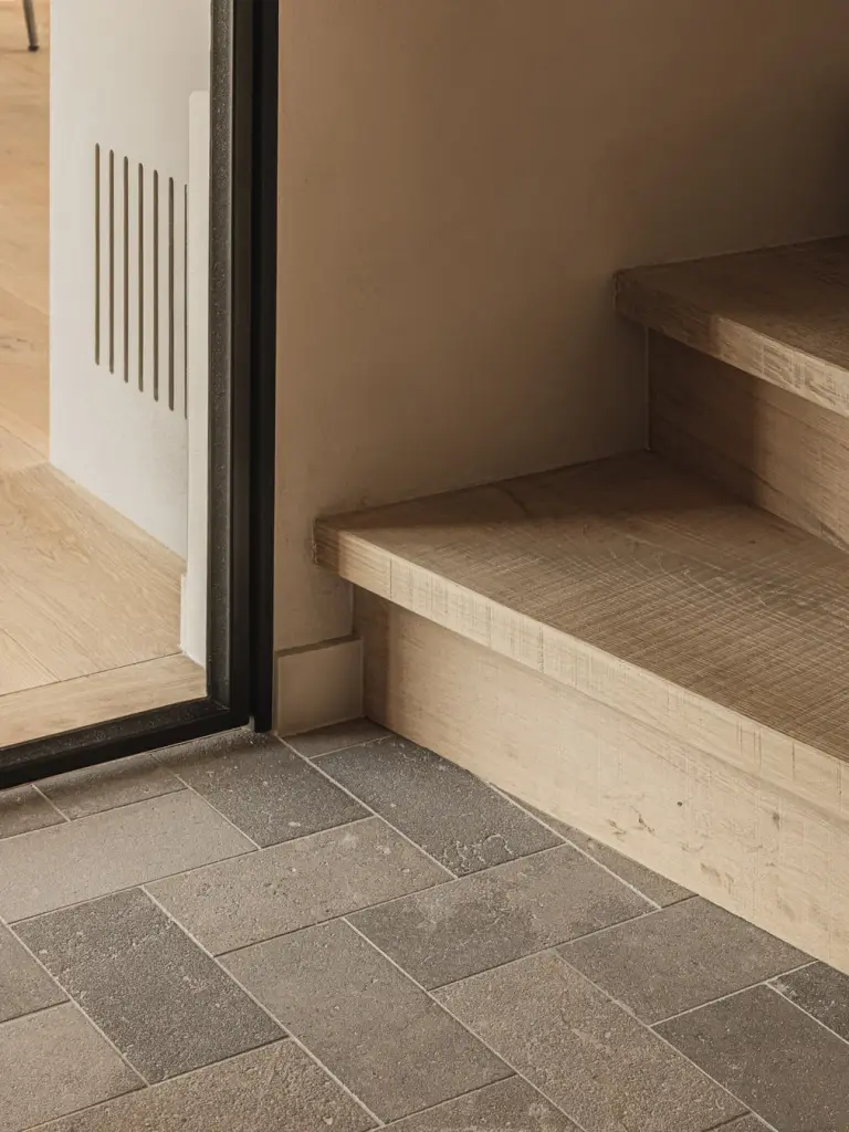 Eikenhouten trede en natuurstenen vloer bij een stalen glasdeur, Landelijke woning in Torhout, interieur Laura Calleeuw