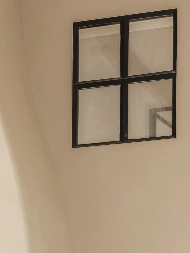 Klein zwart stalen raam in een kalkpleisterwand, Landelijke woning in Torhout, interieur Laura Calleeuw