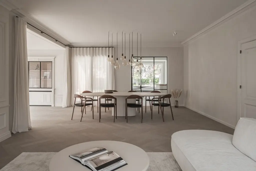 Doorkijk door de eetkamer met ovale tafel en hanglampen naar de woonkamer met sofa en salontafel, Herenhuis in Roeselare, interieur Laura Calleeuw