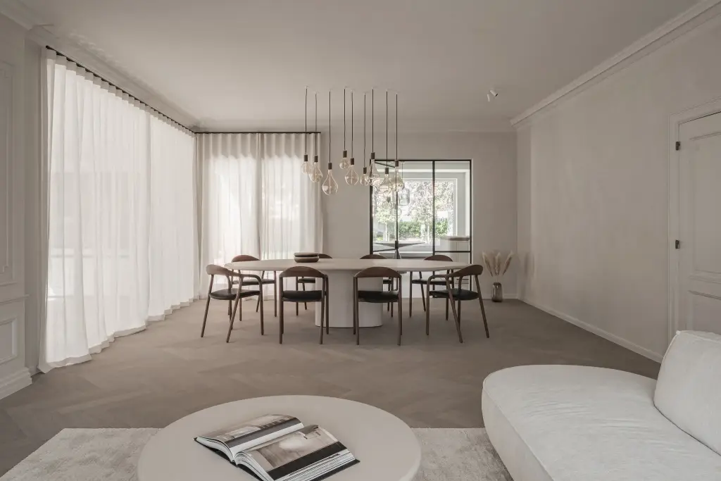 Doorkijk door de eetkamer met ovale tafel en hanglampen naar de woonkamer met sofa en salontafel, Herenhuis in Roeselare, interieur Laura Calleeuw