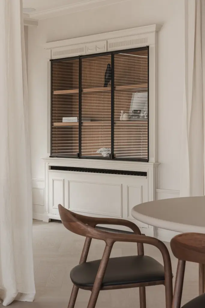 Eikenhouten stoel naast een witte kast met stalen vitrinedeuren, Herenhuis in Roeselare, interieur Laura Calleeuw
