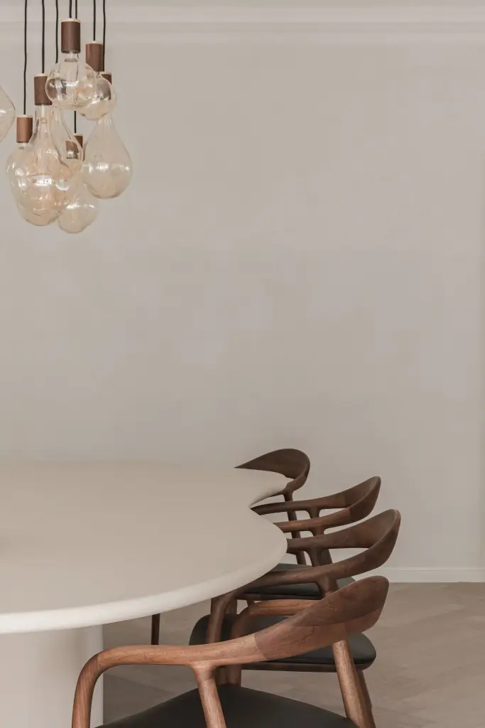 Hanglampen met koperen kap en gloeilamp boven de ovale tafel met eiken stoelen, Herenhuis in Roeselare, interieur Laura Calleeuw