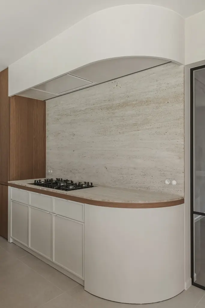 Keuken met gebogen hoek, travertijnen achterwand en een boogvormig plafond boven het gasfornuis, Herenhuis in Roeselare, interieur Laura Calleeuw