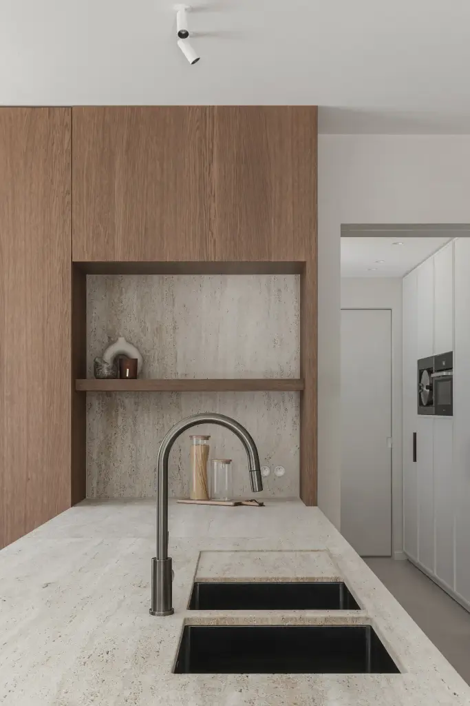 Keukeneiland met spoelbak, kraan en een nis met planken en decoratie tegen travertijn, Herenhuis in Roeselare, interieur Laura Calleeuw