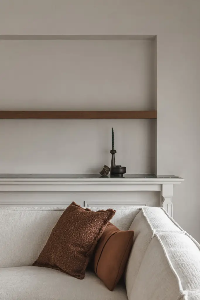 Nis met eikenhouten plank en sculpturen boven de sofa met kussens, met en zonder indirecte verlichting, Herenhuis in Roeselare, interieur Laura Calleeuw