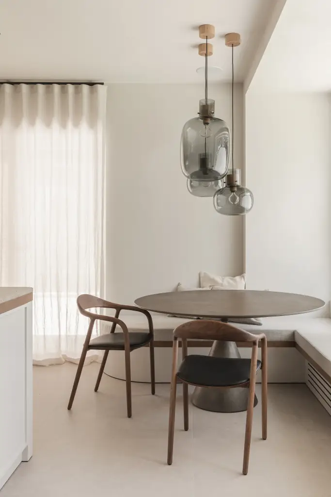 Ontbijthoek met ronde tafel, houten stoelen, hoekbank en grijze glazen hanglampen, Herenhuis in Roeselare, interieur Laura Calleeuw