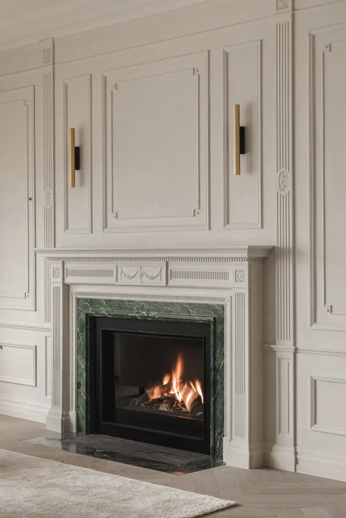 Open haard met groen marmeren omlijsting, vuur en messing wandlampen tegen de lambrisering, Herenhuis in Roeselare, interieur Laura Calleeuw