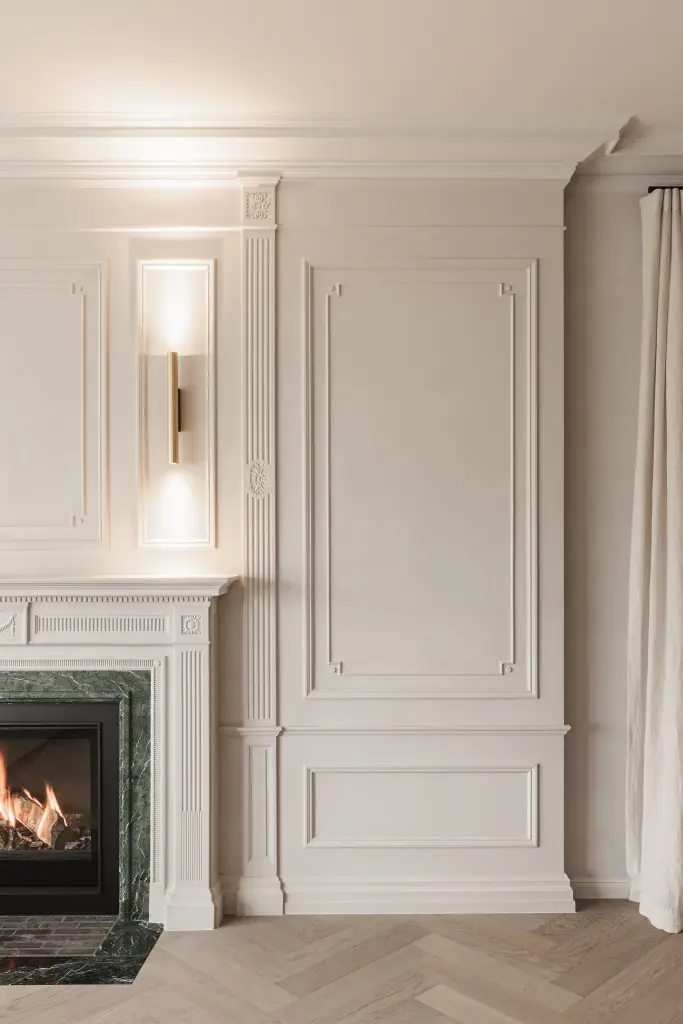 Klassieke schouw met lambrisering en een messing wandlamp, met en zonder verlichting, centuries of elegance, thoughtfully reimagined for today, interieur Laura Calleeuw