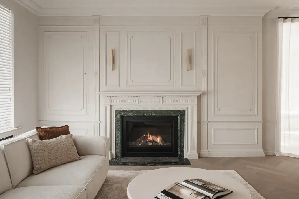 Woonkamer met open haard in groen marmer, lambrisering, messing wandlampen en een sofa, met en zonder verlichting, Herenhuis in Roeselare, interieur Laura Calleeuw