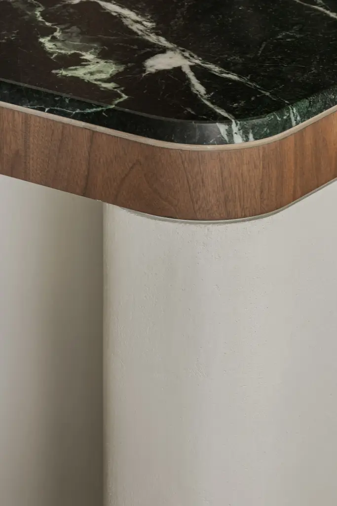 Afgeronde hoek van het keukeneiland met marmeren blad en walnoten rand, Compact appartement in Knokke, interieur Laura Calleeuw