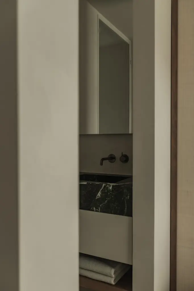 Doorkijk naar de badkamer met wastafel in groen marmer, Compact appartement in Knokke, interieur Laura Calleeuw