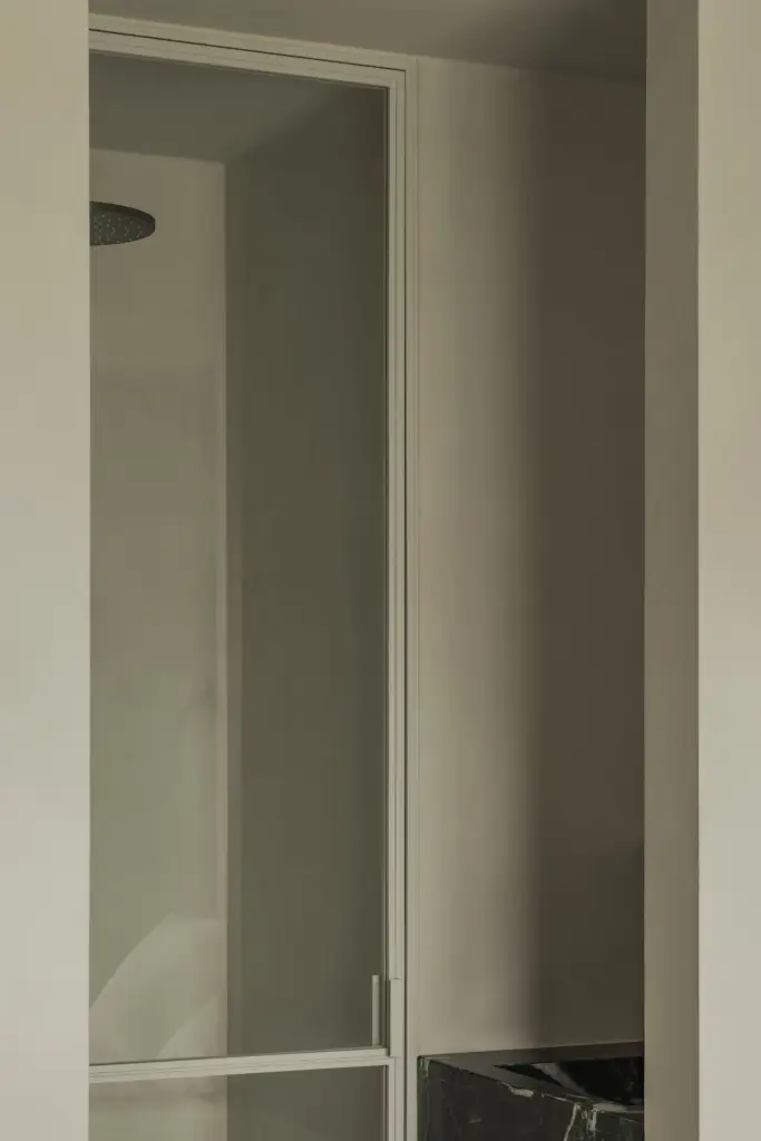 Badkamer achter glazen deur met zwart staalprofiel, Compact appartement in Knokke, interieur Laura Calleeuw