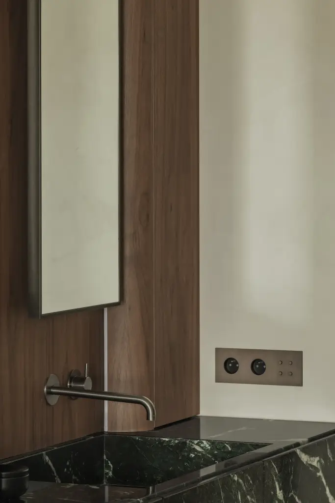 Badkamer met wastafel in groen marmer, smalle spiegels en wandlamp, Compact appartement in Knokke, interieur Laura Calleeuw