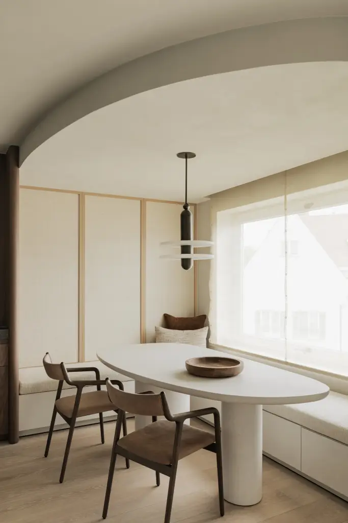 Eethoek onder een gewelfd plafond met ovale tafel en hanglamp, Compact appartement in Knokke, interieur Laura Calleeuw