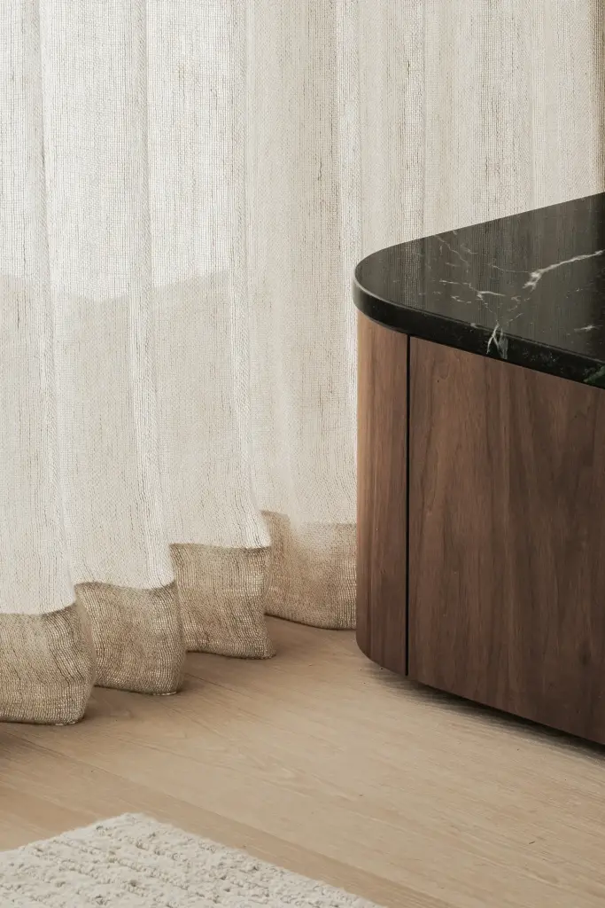 Linnen gordijn naast een afgerond meubel met groen marmeren blad, Compact appartement in Knokke, interieur Laura Calleeuw
