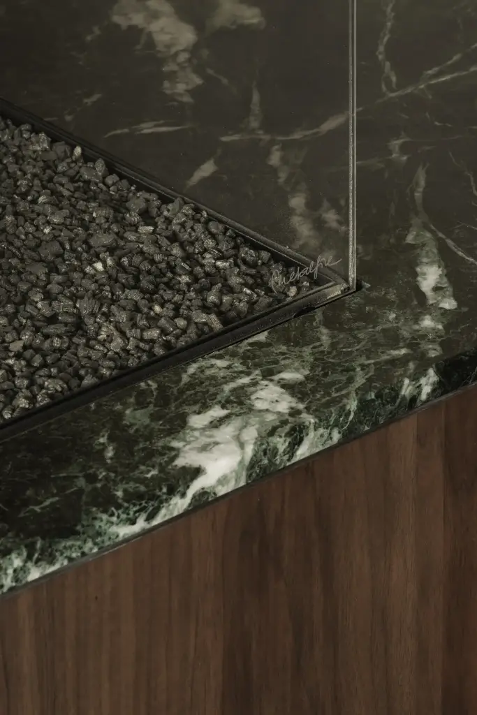 Detail van groen marmeren blad met glas en keien van de haard, Compact appartement in Knokke, interieur Laura Calleeuw