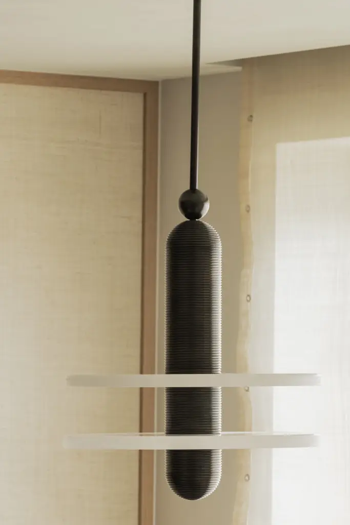 Zwart-witte hanglamp tegen een rieten wandbekleding, Compact appartement in Knokke, interieur Laura Calleeuw