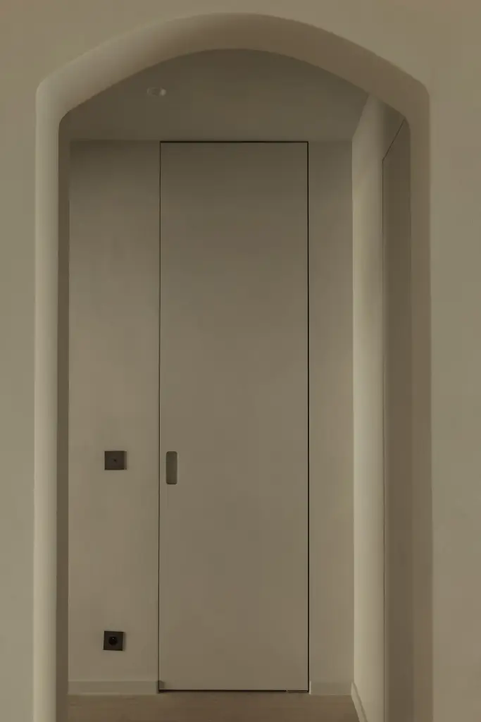 Onzichtbare inbouwdeur in een gewelfde nis met microcement afwerking, Compact appartement in Knokke, interieur Laura Calleeuw