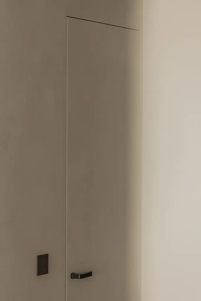 Onzichtbare inbouwdeur in een gewelfde nis met microcement afwerking, Compact appartement in Knokke, interieur Laura Calleeuw