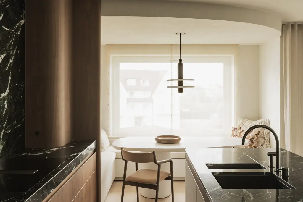 Keuken met groen marmeren werkblad, walnoten kolom en eethoek met ovale tafel, Compact appartement in Knokke, interieur Laura Calleeuw