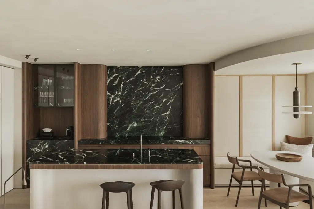 Keuken met marmeren achterwand, eiland, ovale eettafel en zitbank, Compact appartement in Knokke, interieur Laura Calleeuw