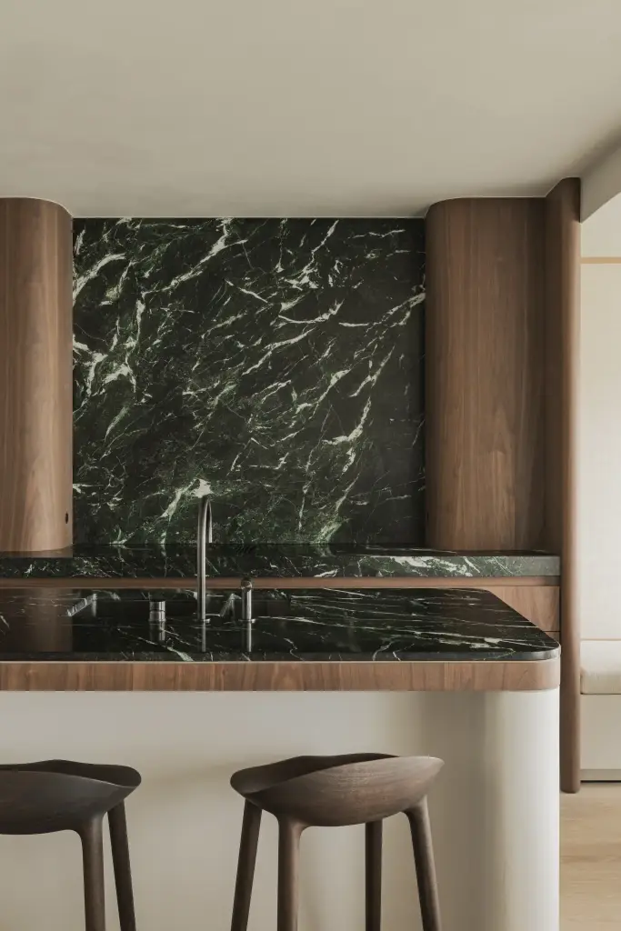 Keukeneiland met twee barkrukken voor een marmeren achterwand, Compact appartement in Knokke, interieur Laura Calleeuw