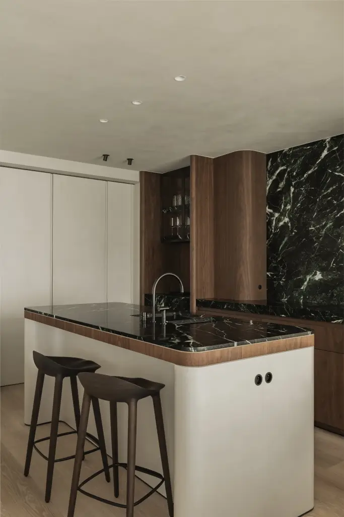 Keukeneiland met groen marmeren blad en houten barkrukken, Compact appartement in Knokke, interieur Laura Calleeuw