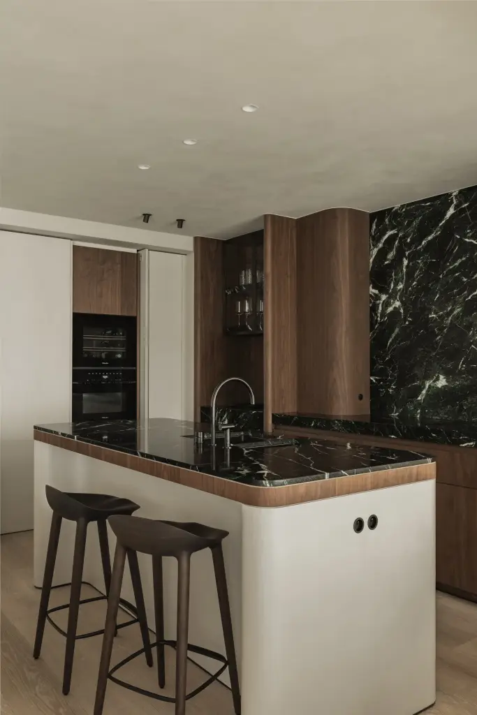 Keukeneiland met groen marmeren blad en houten barkrukken, Compact appartement in Knokke, interieur Laura Calleeuw