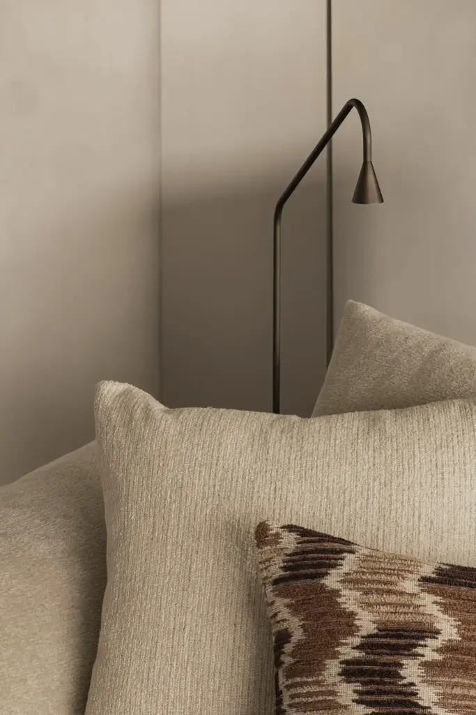 Detail van een sierkussen en zwarte staande leeslamp, Compact appartement in Knokke, interieur Laura Calleeuw
