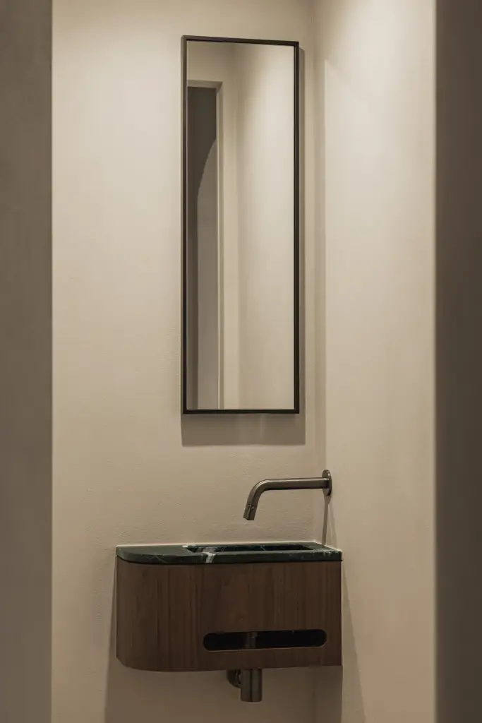 Toilet met wandfonteintje in groen marmer en walnoten onderkast, Compact appartement in Knokke, interieur Laura Calleeuw
