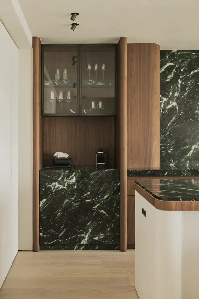 Vitrinekast met glazen deuren, walnoot en wijnglazen naast marmer, Compact appartement in Knokke, interieur Laura Calleeuw