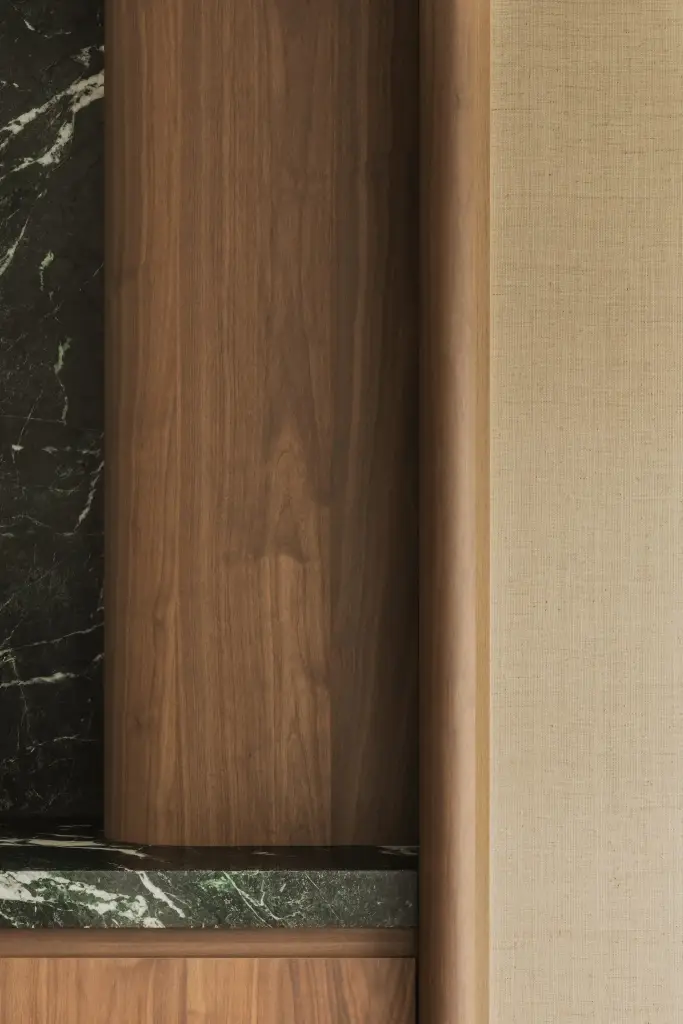 Detail van walnoten kolom tussen groen marmer en rieten wandbekleding, Compact appartement in Knokke, interieur Laura Calleeuw