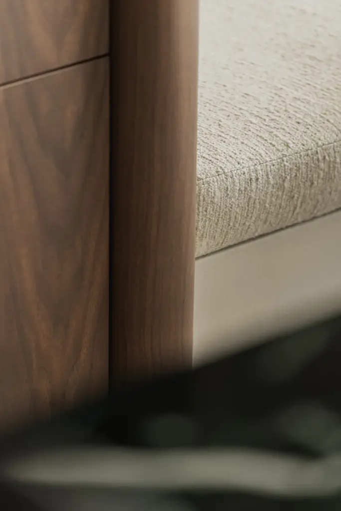Detail van een walnoten kolom naast een zitbank in bouclé, Compact appartement in Knokke, interieur Laura Calleeuw