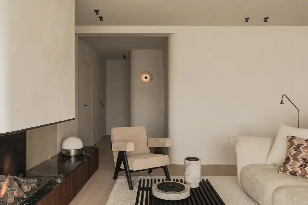Woonkamer met open haard, bouclé zetel en fauteuil in zwart hout, Compact appartement in Knokke, interieur Laura Calleeuw