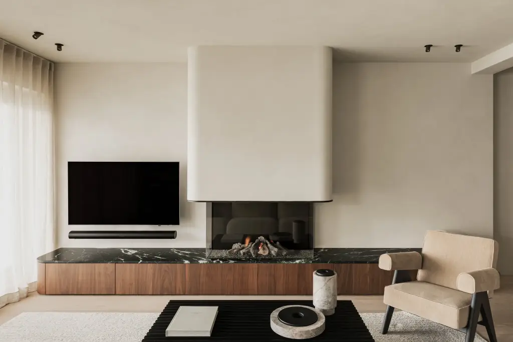 Woonkamer met televisie boven een open haard met marmeren blad en walnoten onderkast, Compact appartement in Knokke, interieur Laura Calleeuw