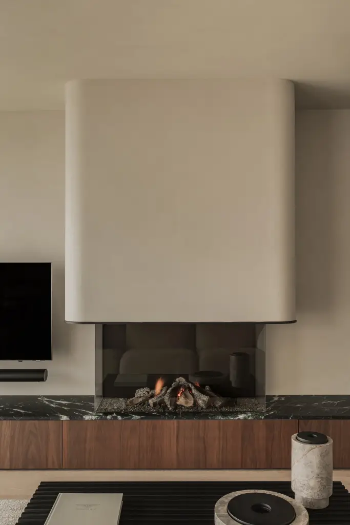 Woonkamer met televisie boven een open haard met marmeren blad en walnoten onderkast, Compact appartement in Knokke, interieur Laura Calleeuw