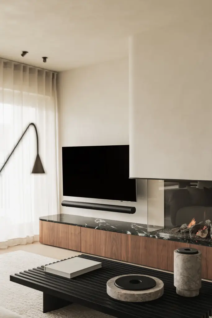 Woonkamer met televisie boven een open haard met marmeren blad en walnoten onderkast, Compact appartement in Knokke, interieur Laura Calleeuw