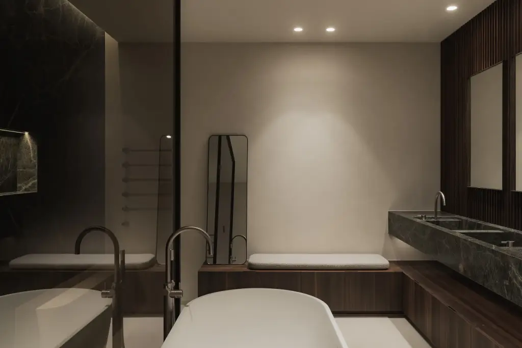 Badkamer met vrijstaand bad, dubbele wastafel in marmer en donkere lamellenwand, Nieuwbouwwoning in Roeselare, interieur Laura Calleeuw