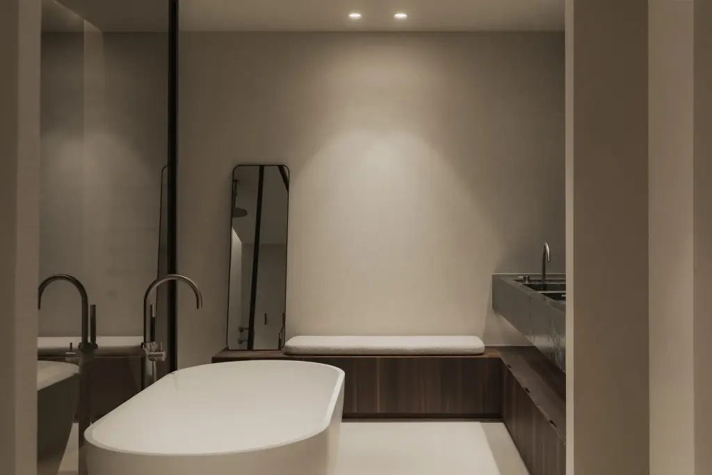 Badkamer met vrijstaand bad, dubbele wastafel in marmer en donkere lamellenwand, Nieuwbouwwoning in Roeselare, interieur Laura Calleeuw
