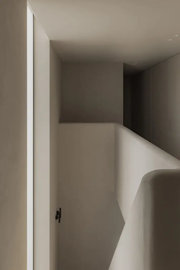 Gang met inbouwkasten en afgeronde trapleuning in microcement, Nieuwbouwwoning in Roeselare, interieur Laura Calleeuw