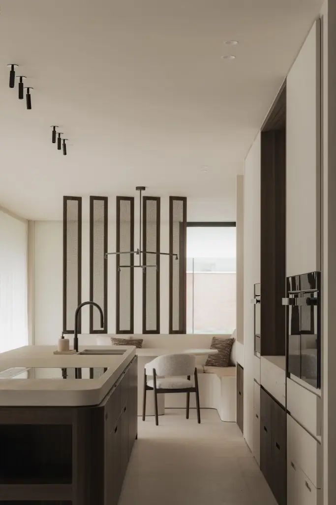 Keuken met afgerond eiland, glazen lamellenscherm en eethoek op de achtergrond, Nieuwbouwwoning in Roeselare, interieur Laura Calleeuw