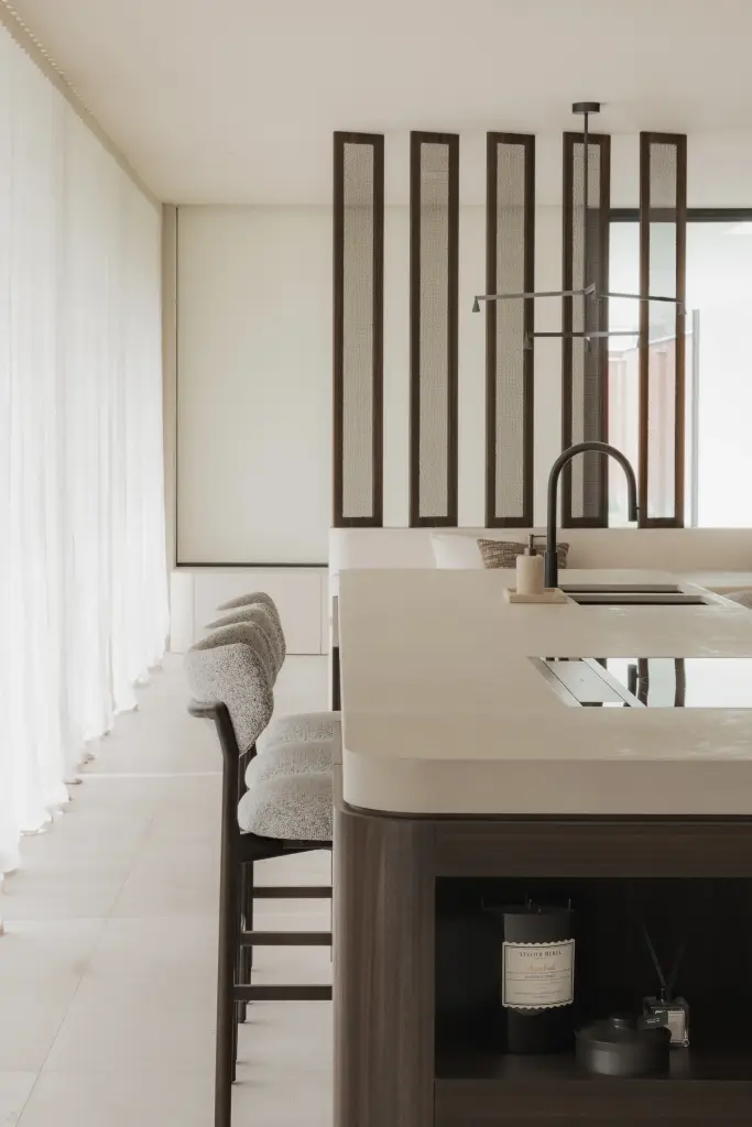Keuken met afgerond eiland, glazen lamellenscherm en eethoek op de achtergrond, Nieuwbouwwoning in Roeselare, interieur Laura Calleeuw