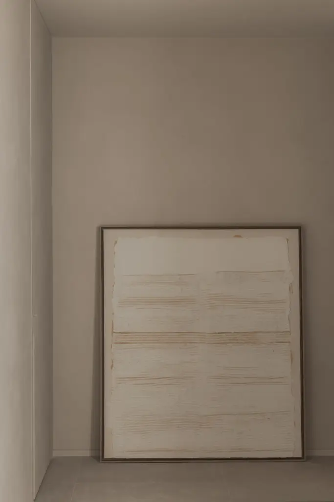 Groot wit schilderij in houten lijst tegen een microcement wand, Nieuwbouwwoning in Roeselare, interieur Laura Calleeuw