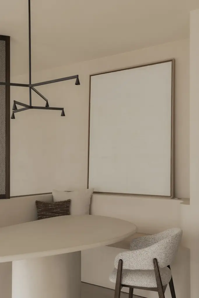 Zitbank met sierkussen onder een wit schilderij in de eethoek, Nieuwbouwwoning in Roeselare, interieur Laura Calleeuw