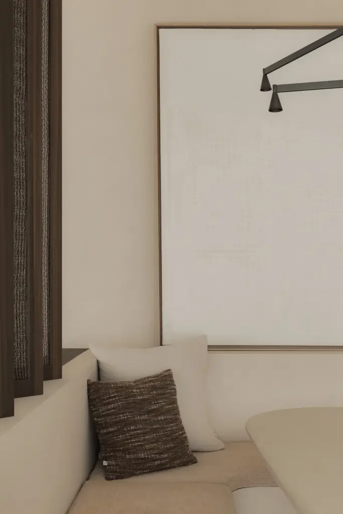 Zitbank met sierkussen onder een wit schilderij in de eethoek, Nieuwbouwwoning in Roeselare, interieur Laura Calleeuw