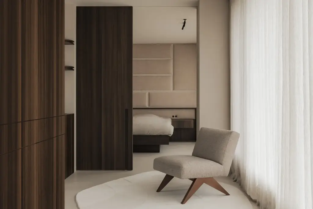 Slaapkamer met fauteuil op rond tapijt, kleerkast en gestoffeerd hoofdbord, Nieuwbouwwoning in Roeselare, interieur Laura Calleeuw