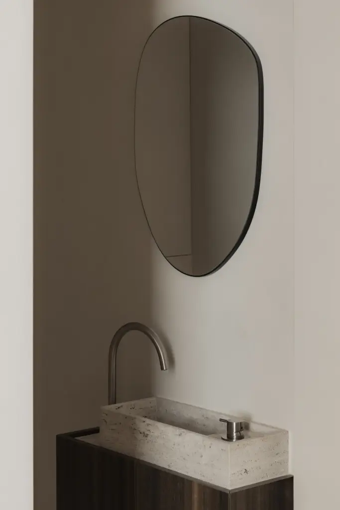 Toilet met travertijn wandfontein, zwarte kraan en ovale spiegel, Nieuwbouwwoning in Roeselare, interieur Laura Calleeuw